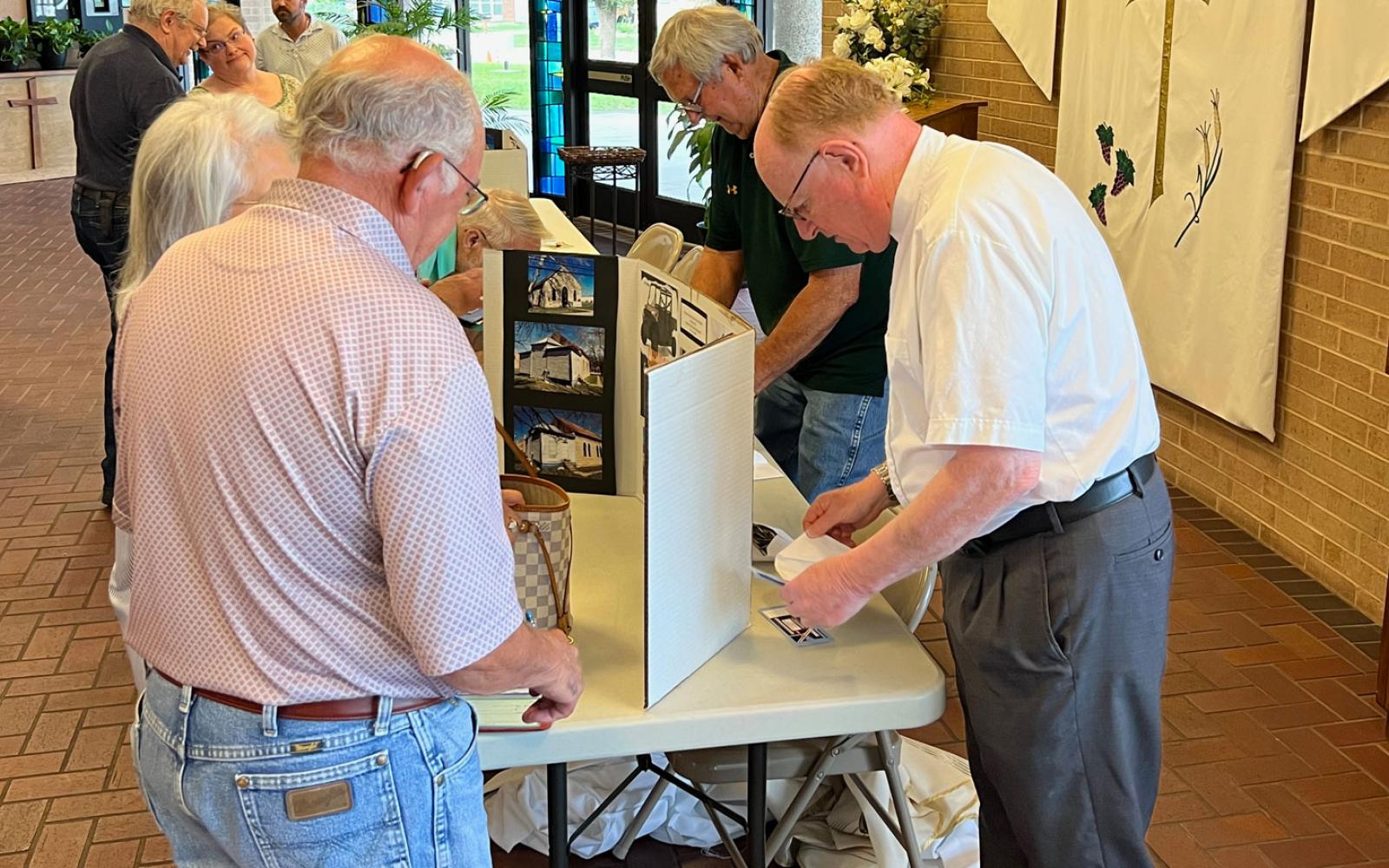 Father Mark Woodruff (right), pastor of the Sacred Heart Church in Menard, sells raffle tickets and collects donations for the restoration of the 1899 church at Holy Angels Catholic Church in San Angelo on May 20, 2023. 