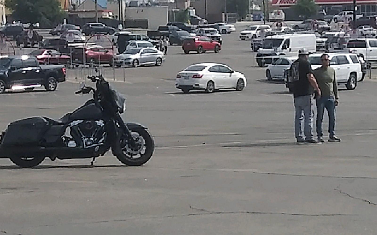 One of the two males to the right of the motorcycle confronted the mysterious bus's driver.